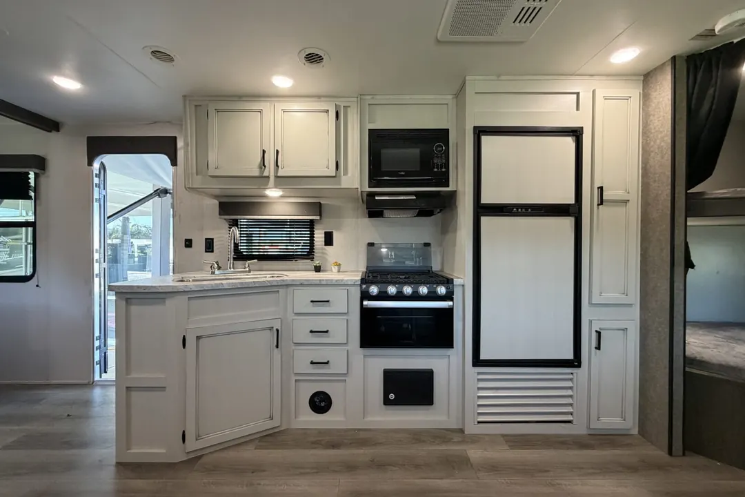 The kitchen of a 2021 Highland Ridge Open Range with the stove, sink and fridge